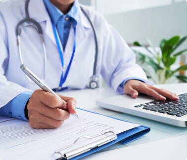 doctor filling out medical paperwork at their desk